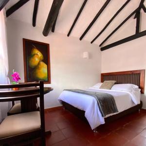 1 dormitorio con 1 cama, 1 mesa y 1 pintura en Hotel Evoque Sáchica, en Villa de Leyva