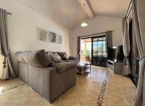 a living room with a couch and a tv at Villa Eva - New to the market, fully refurbished licensed villa - private pool in Caleta De Fuste