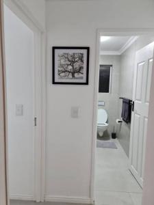 a white hallway with a bathroom with a picture on the wall at Cozy 2 bedroom APT - Near Kenilworth Racecourse in Cape Town