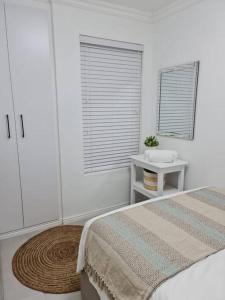 Habitación blanca con cama y ventana en Cozy 2 bedroom APT - Near Kenilworth Racecourse, en Ciudad del Cabo