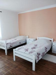 two white beds in a room with wooden floors at Apartman Kristina in Čapljina