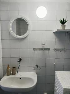a white bathroom with a sink and a mirror at Apartman Kristina in Čapljina