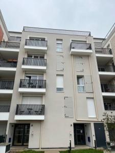 - un bâtiment blanc avec des balcons sur le côté dans l'établissement T3 65 m2 avec parking 15 mns Paris by immo kit bnb, à Gagny