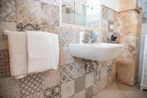 a bathroom with a sink and towels on a wall at Siracusa Casa Tiche & Selene in Syracuse