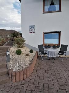 a patio with two chairs and a table in front of a building at Melanies Wohlfühlort in Bruttig-Fankel