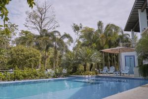 a swimming pool with chairs and an umbrella next to a house at El Bosque Hotel Boutique in Doradal