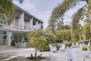 a patio at the resort with white chairs and palm trees at El Bosque Hotel Boutique in Doradal