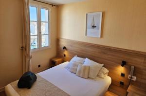 - une chambre avec un lit doté d'oreillers blancs et d'une fenêtre dans l'établissement Hôtel du Port, à Saint-Martin-de-Ré