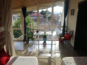 Habitación con ventana grande y mesa con plantas. en Cozy loft, en Korçë
