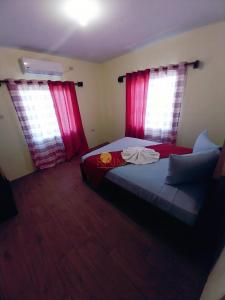 a bedroom with a bed and two windows with red curtains at Highend resort in Buccoo
