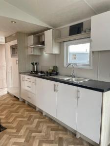 a kitchen with white cabinets and a black counter top at Chalet direct aan Waddenzee in Westerland