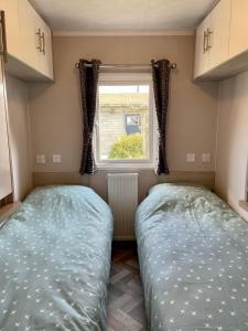 two beds in a small room with a window at Chalet direct aan Waddenzee in Westerland