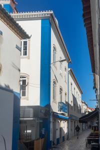 uma pessoa andando por uma rua ao lado de edifícios em TikLiving na Ericeira