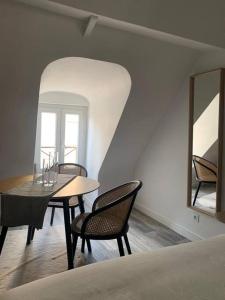 a dining room with a table and chairs and a mirror at appartement catimini in Dijon
