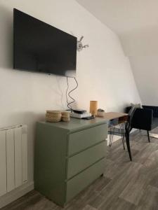Habitación con tocador y TV en la pared. en appartement catimini, en Dijon