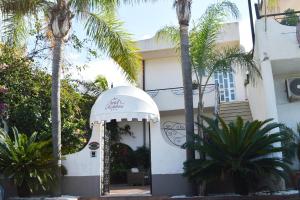 a white house with palm trees in front of it at Hotel Redebora in Torregrotta