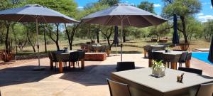 a restaurant with tables and umbrellas on a patio at Mukumbura Swartwater 
