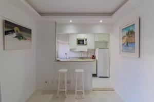 een witte keuken met krukken en een koelkast bij Lobie Ipanema Barão da Torre in Rio de Janeiro