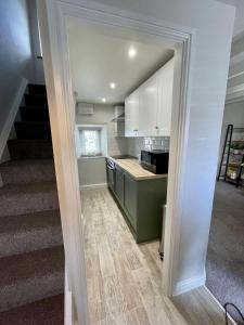 a kitchen with white cabinets and a staircase at Cosy 2 bedroom cottage in Llanuwchllyn