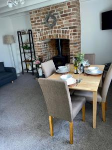 a dining room table with chairs and a brick fireplace at Cosy 2 bedroom cottage in Llanuwchllyn