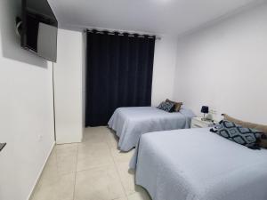 Habitación con 2 camas y TV en la pared. en Apartamentos BARBAS en Villanueva de los Castillejos
