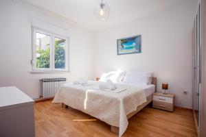 a white bedroom with a bed and a window at Apartments Adisa in Omiš