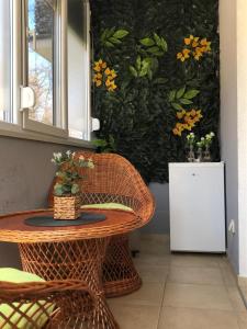 ein Korbtisch und ein Stuhl neben einer Wand mit Blumen in der Unterkunft Apartman Radmanovac 2 in Vrnjačka Banja