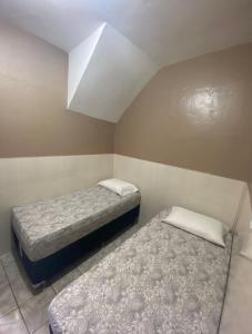 2 camas en una habitación pequeña con techo en Flat da Tássia, en Maragogi