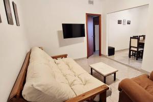 een woonkamer met een bank en een tv bij Casa familiar con patio y parrilla in Tandil