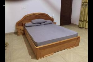 1 cama con marco de madera en un dormitorio en Stunning Executive 2 Bedroom Apartment with KING SIZE BED en Kumasi
