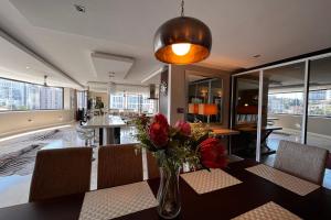 uma sala de jantar com um vaso de flores sobre uma mesa em Luxury Penthouse In The Heart Of Sandton em Joanesburgo