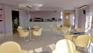 a restaurant with white chairs and tables and a counter at Motel Abalo in Catoira