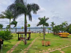 Life Resort Flat - Torre F - Beira do lago في برازيليا: حديقة فيها نخلة وطاولة وشاطئ