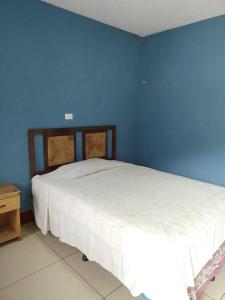 sypialnia z białym łóżkiem w niebieskiej ścianie w obiekcie Hotel y Restaurante Tzutujil w mieście San Lucas Tolimán