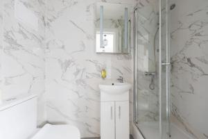 a white bathroom with a shower and a sink at Victorian Windowless Beauty with Private Bath Near Tube Station in London