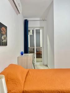 - un lit orange dans une chambre blanche avec une table dans l'établissement Habitación Doble o sencilla en apartamento Compartido en Gzira Malta , zona centrica, à Il-Gżira