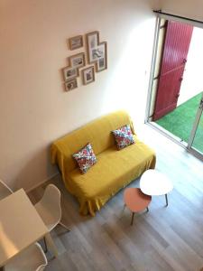 a living room with a yellow couch and a table at Appartement climatisé avec jardin et pkg privatif in Cap d'Agde