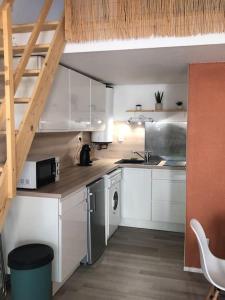 a small kitchen with white cabinets and a staircase at Appartement climatisé avec jardin et pkg privatif in Cap d'Agde