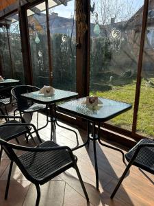 - deux tables et des chaises dans une chambre avec fenêtres dans l'établissement Stajnia Bukwica, à Narewka