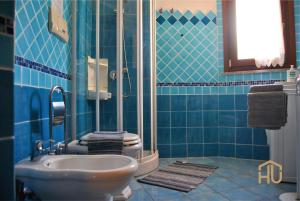 bagno piastrellato blu con servizi igienici e lavandino di Villa Pietra Rossa a Budoni