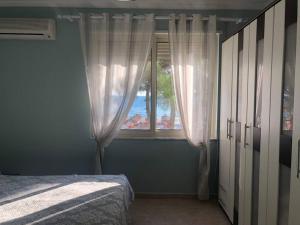 a bedroom with a bed and a window with the ocean at Pandora's Seaview Apartment in Durrës
