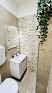 La salle de bains est pourvue de toilettes, d'un lavabo et d'une plante. dans l'établissement Viareggio Deluxe, à Viareggio