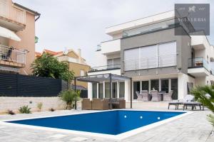 a house with a blue swimming pool in front of it at VILLA LJUBAS in Srima