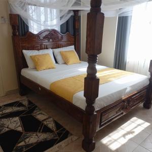 1 dormitorio con cama de madera y almohadas amarillas en Cozy Apartment - Nyali Mombasa, en Mombasa