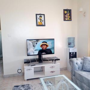 a living room with a tv on a white wall at Cozy Apartment - Nyali Mombasa in Mombasa