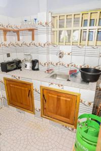 a kitchen with wooden cabinets and a tiled floor at Le Doux Refuge in Djérigbé