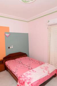 a bedroom with a bed with pink sheets and a ceiling at Le Doux Refuge in Djérigbé