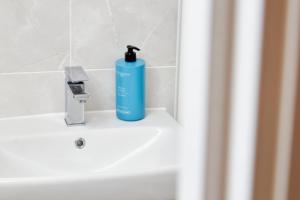 a blue bottle of soap sitting on top of a sink at Superb 3BR House in Coventry Sleeps 9 w/Parking in Canley