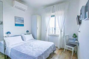 a white bedroom with a bed and a desk and a window at Hotel Premuda in Spotorno