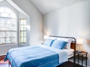 a bedroom with a bed with blue sheets and a window at Lovely 2 bedroom, 1 bath condo with pools and gym. in Houston